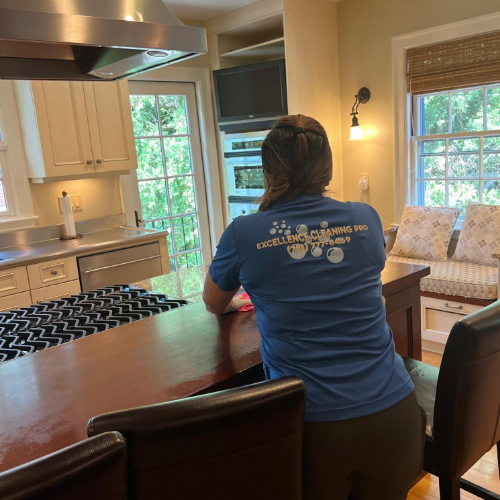 crew Cleaner wiping a desk in a living room with flexible cleaning schedules in Boston.