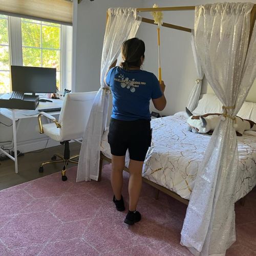 11 Cleaner making a bed in a bedroom with eco-friendly products in Boston.